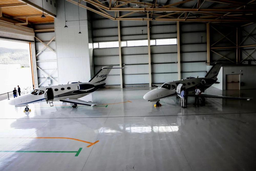 Two Cessna Citation Mustang private jets parked side by side inside the Encamp hangar of Andorra Jets