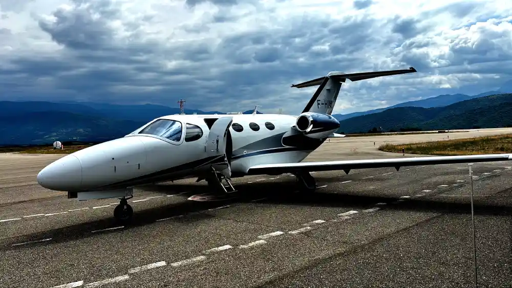 A Cessna Citation Mustang of Andorra Jets parked on a mountain runway under dramatic Pyrenees clouds